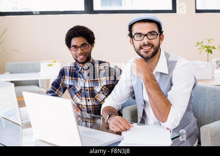 Smiling gay couple using laptops Stock Photo