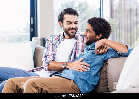 Happy gay couple talking on sofa Stock Photo
