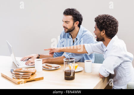 Happy gay couple having breakfast and using laptop Stock Photo