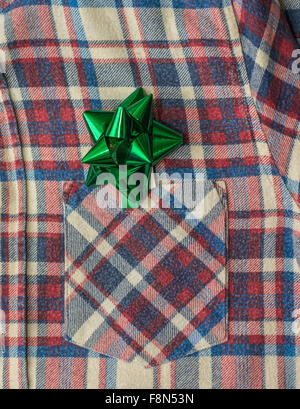 Overhead shot of a man's plaid shirt with Christmas gift bow. Stock Photo