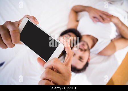 Happy gay couple taking selfie on bed Stock Photo