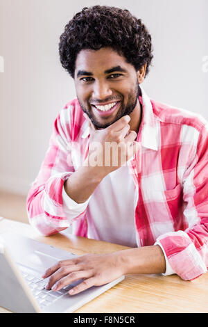 Smiling man using laptop and looking at the camera Stock Photo