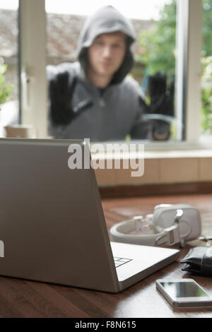 Burglar Looking At Valuables Through House Window Stock Photo