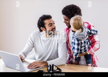 Happy gay couple with child using laptop Stock Photo