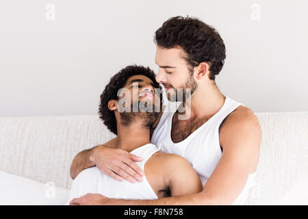 Happy gay couple cuddling on bed Stock Photo