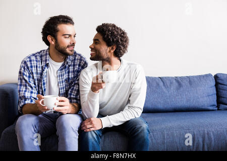 Happy gay couple talking on sofa Stock Photo