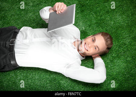 Young businessman lying on green grass Stock Photo