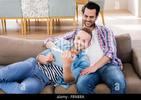 Gay couple relaxing on the couch using tablet Stock Photo