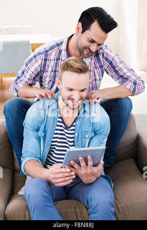 Gay couple relaxing on the couch using tablet Stock Photo