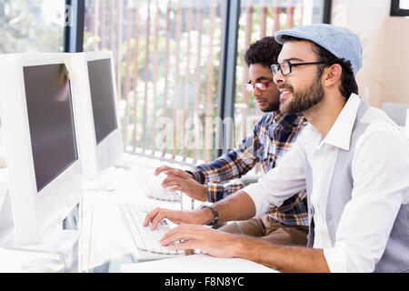 Smiling gay couple working on computers Stock Photo
