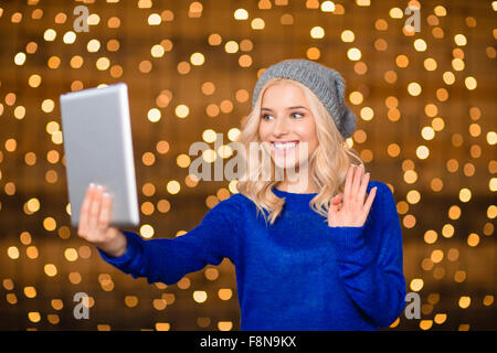 Portrait of a happy woman doing video call on tablet computer over holiday lights on background Stock Photo