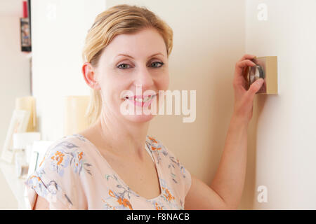 Woman Adjusting Central Heating Thermostat Control Stock Photo