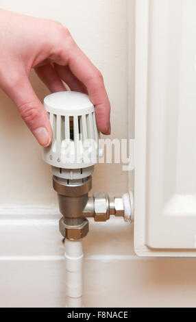 Hand Adjusting Thermostat On Radiator Valve Stock Photo