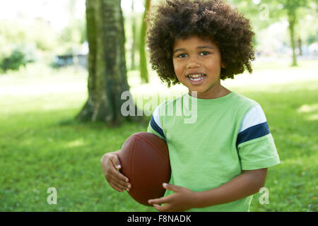 Excited Young Boy Playing American Football In Park