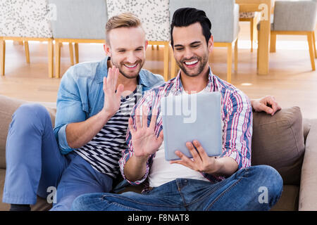 Gay couple relaxing on the couch using tablet Stock Photo