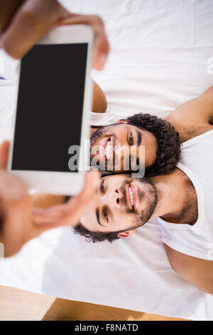 Happy gay couple taking selfie on bed Stock Photo