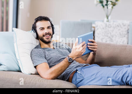 Smiling man using tablet and headphones Stock Photo