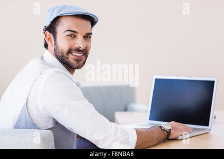 Smiling man using laptop looking back at the camera Stock Photo
