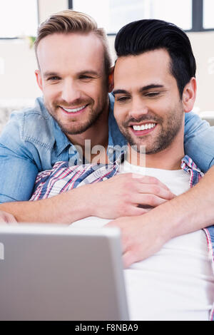 Gay couple relaxing on the couch using laptop Stock Photo