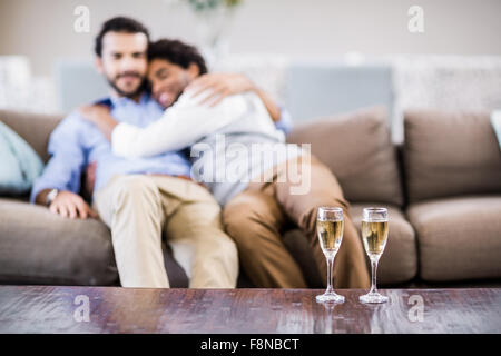 Relaxed gay couple hugging on sofa Stock Photo