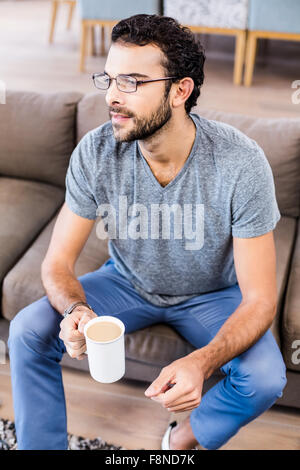 Attractive man sitting on sofa holding coffee Stock Photo