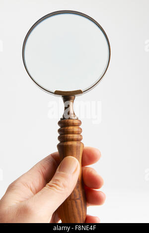 Hand Holding Magnifying Glass Against White Background Stock Photo