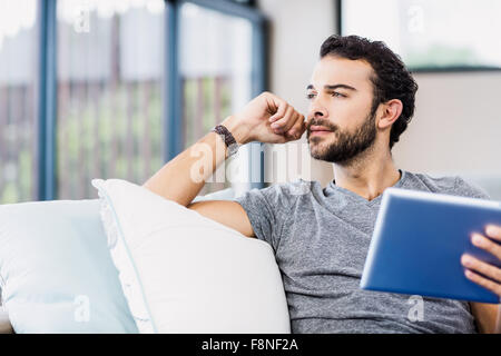 Thoughtful man holding tablet Stock Photo