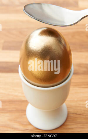 Spoon Cracking Golden Egg Stock Photo