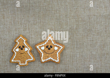 close up of two Christmas cookies, star shape and Christmas tree, smiling on  canvas with copy space, horizontal Stock Photo