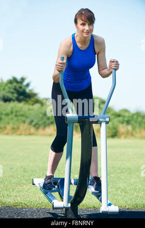 Middle Aged Woman Using Outdoor Gym Equipment Stock Photo