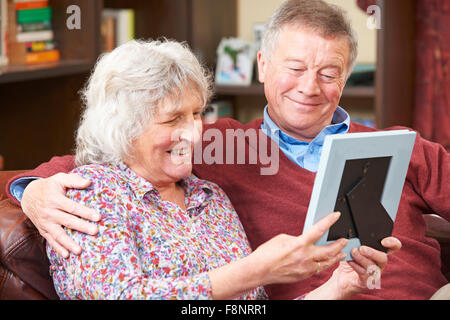 Senior Couple Looking At Photograph In Frame Together Stock Photo