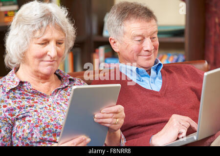 Senior Couple Using Digital Tablet And Laptop At Home Stock Photo