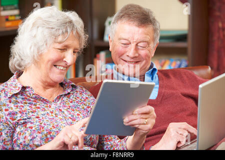 Senior Couple Using Digital Tablet And Laptop At Home Stock Photo