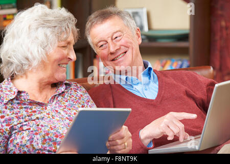 Senior Couple Using Digital Tablet And Laptop At Home Stock Photo