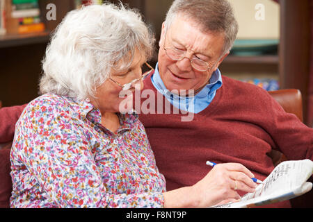 Senior Couple Doing Crossword Puzzle In Newspaper Together Stock Photo