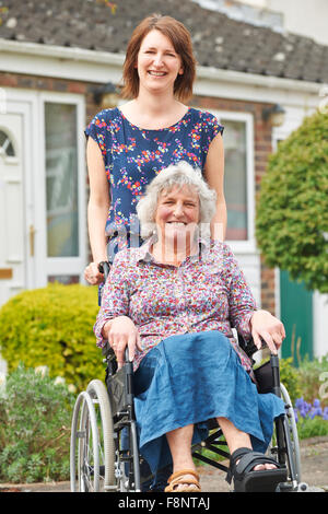 Adult Daughter Pushing Mother In Wheelchair Stock Photo