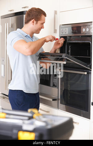 Man Repairing Domestic Oven In Kitchen Stock Photo