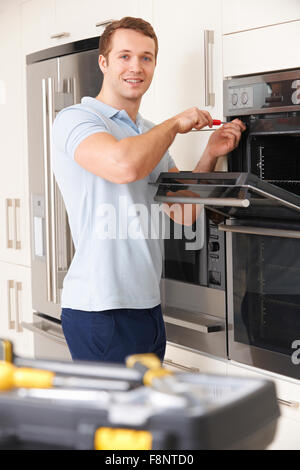 Man Repairing Domestic Oven In Kitchen Stock Photo