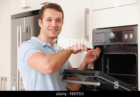 Man Repairing Domestic Oven In Kitchen Stock Photo