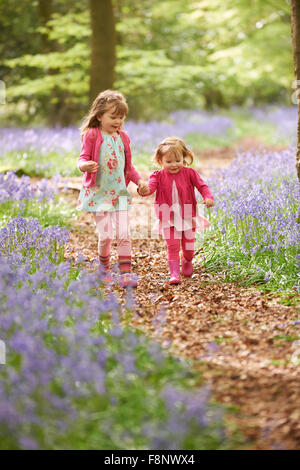 Two Girls Running Through Bluebell Woods Together Stock Photo