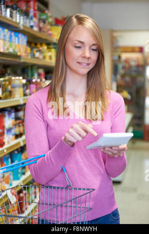 Woman Using Calculator Whilst Shopping In Supermarket Stock Photo