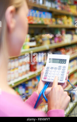 Woman Using Calculator Whilst Shopping In Supermarket Stock Photo