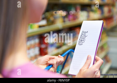 Woman Looking At Shopping List In Supermarket Stock Photo
