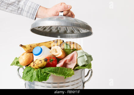 Hand Putting Lid On Garbage Can Full Of Waste Food Stock Photo