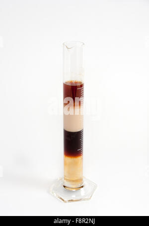close-up of a tall and narrow berzelius glass filled with a four layered coffee cocktail, with alternating liquids alternating i Stock Photo