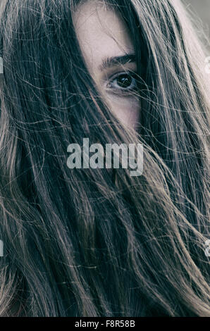 Sad teenage girl hair covering face outdoors Stock Photo