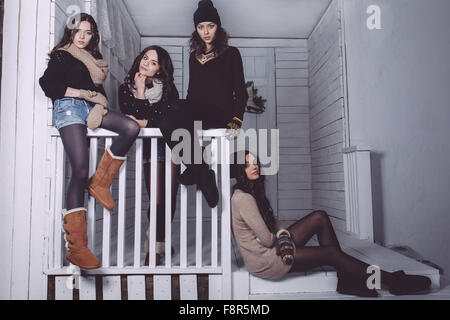 Four stylish models posing sitting on the fence Stock Photo