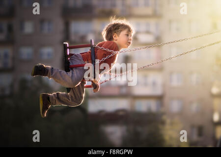 Boy on a swing in playground Stock Photo