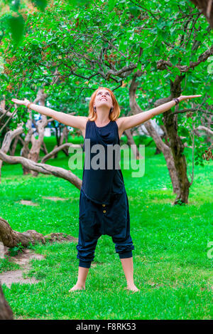 happy girl doing yoga on the grass in the park Stock Photo