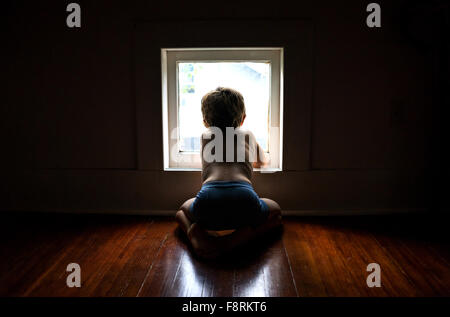 Boy sitting on floor looking out of a window